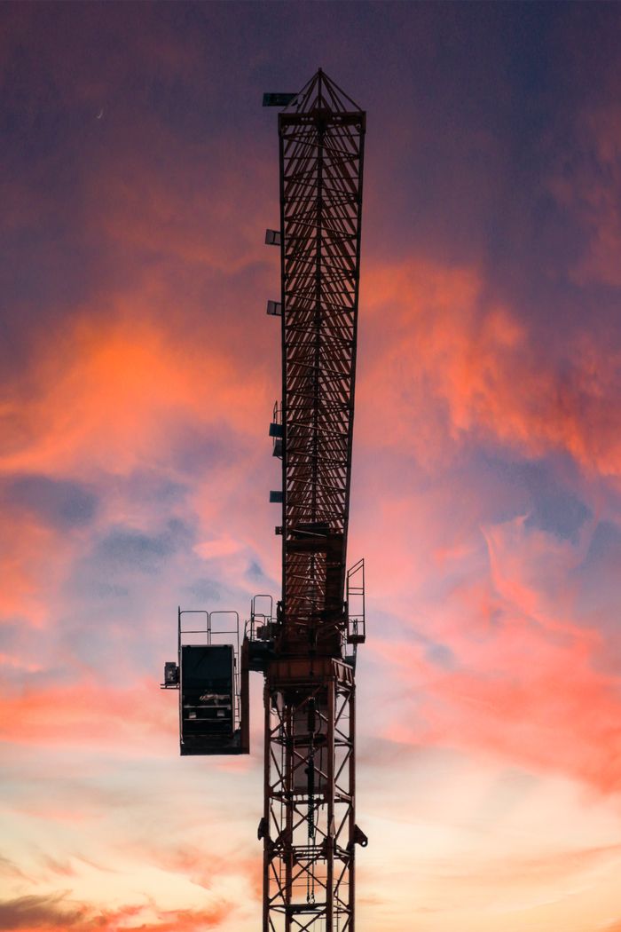The Art of Drawing Readers In: Your attractive post title goes here A silhouette of a towering construction crane set against a vibrant sunset sky.