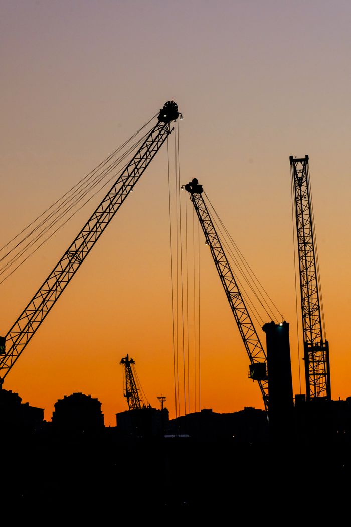 Crafting Captivating Headlines: Your awesome post title goes here Silhouetted construction cranes against a vibrant sunset sky in an urban landscape.
